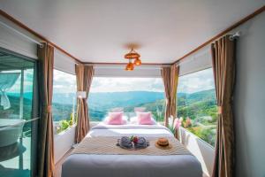 a bedroom with a bed and a large window at ชิวชิวแคมป์ ภูชี้ฟ้า in Ban Huai Han