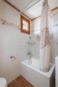a bathroom with a tub and a shower curtain at Casa di levante - Glossa Skopelos in Loutraki