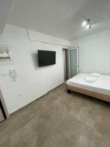 een witte kamer met een bed en een flatscreen-tv bij Central Studio next to Metro in Piraeus