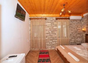 Un dormitorio con una cama y una pared de piedra. en Zilfe Guesthouse, en Gjirokastra