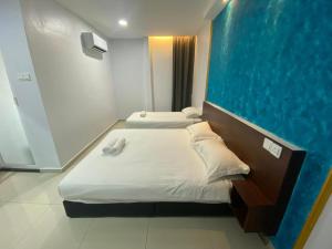 two beds in a room with a blue wall at Codidik Hotel in Kuantan +20 photos