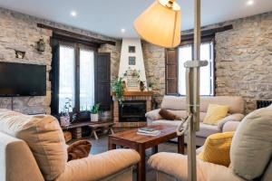 a living room with stone walls and couches and a tv at El Reinazu in Cangas de Onís