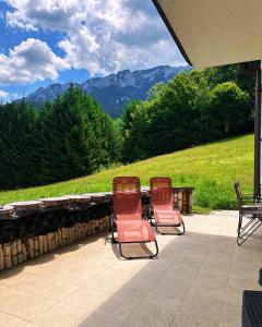 due sedie sedute su un patio con montagne sullo sfondo di Villa & Spa Plaiul Foii - Sierra Blanca a Zărneşti