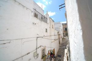 an alley with stairs and windows on a white building at Casa Giglio in Ostuni +25 photos