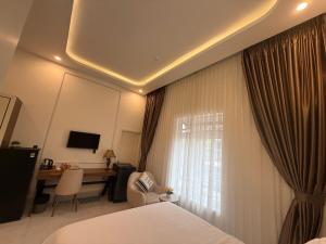 a bedroom with a bed and a desk and a window at Misona The Hotel in Long Thành