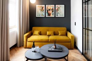 a living room with a yellow couch and two tables at Grodzka Boutique Aparthotel - Stare Miasto in Jelenia Góra