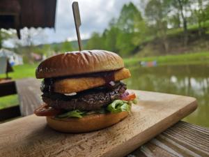 a hamburger sitting on top of a wooden board at Restauracja Hotel Koło do Wozu in Żołobek
