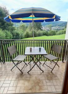 a table and chairs with an umbrella on a balcony at La Monarde in Gérardmer +3 photos