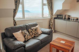 a living room with a leather couch and a table at Plas Gorwelion guest house - Adult only in Llandudno