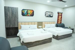 une chambre d'hôtel avec deux lits et deux chaises dans l'établissement RMV Inn, à Vellore