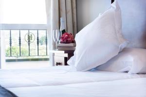 a bed with white sheets and pillows and a window at Hotel Toboso Chaparil in Nerja