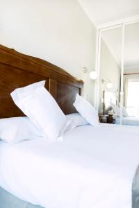 a bedroom with a bed with white pillows and a mirror at Hotel Toboso Chaparil in Nerja