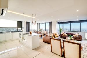 an open kitchen and living room with couches and windows at Luxury 2BR Sky Suite City Views & Prime Location in Cape Town