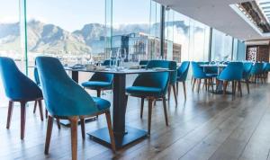 a dining room with blue chairs and a table at Luxury 2BR Sky Suite City Views & Prime Location in Cape Town