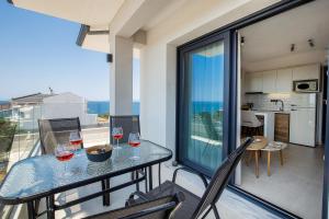 a balcony with a table with wine glasses on it at Emmeli's de lux apartments in Skala Marion