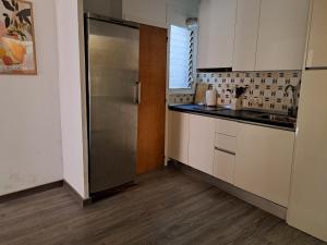 a kitchen with white cabinets and a stainless steel refrigerator at Habitación en el centro histórico de Tarragona in Tarragona +8 photos