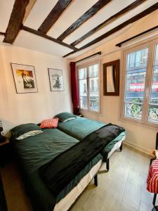 a bedroom with a green bed in a room with windows at LE Globe in Paris