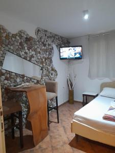 een slaapkamer met een bed, een bureau en een tv bij Vila Verica M in Kravlja
