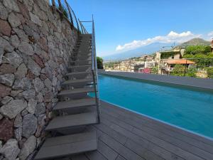 a staircase next to a stone wall next to a swimming pool at Casa DiMa - La Pigna Verde in Taormina