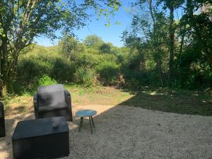 two chairs and a stool sitting on the ground at Tiny sur Conie Avec volupté in Nottonville