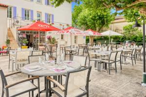 a group of tables and chairs with red umbrellas at Hotel Restaurant Le Castel Fleuri in Carnoules