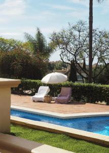 two chairs and an umbrella next to a pool at Elviria Hills Living in Marbella