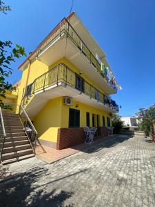 a yellow building with stairs and a balcony at Kapo Residence in Vlorë