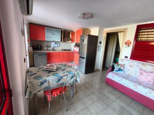 eine Küche mit einem Tisch und eine kleine Küche mit roten Schränken in der Unterkunft La casa di Arianna in Peschici