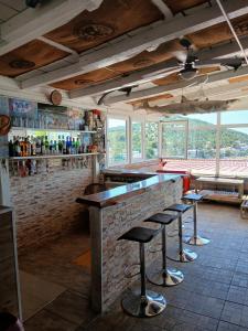 een bar met krukken in een kamer met ramen bij Apartmenthaus Kornatiblick in Tisno