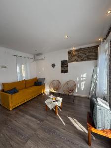 a living room with a yellow couch and chairs at Olive Stonehouse in Plomarion
