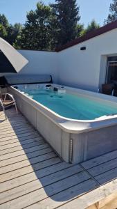 a hot tub on a deck with an umbrella at Le Chalet de la Répandise - Gîte Vosges 9 pers, Spa privé & Piscine - Proche Gérardmer in Laveline-du-Houx