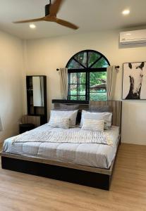 a bedroom with a large bed and a window at Chalong Home Phuket in Phuket