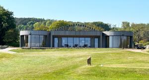 a large building on a grassy field with trees at Coastal Eco-Lodge with hottub Charleton Estate in Elie +21 photos