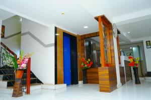 Un vestíbulo con una puerta colorida y flores en jarrones. en Nortels Heights Hotel Apartments, en Chennai