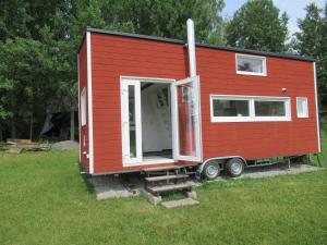 a red tiny house on a trailer in a field at Stuga med bastu i naturen nära Stockholm in Järna