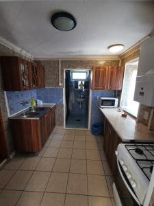 a kitchen with wooden cabinets and a sink and a stove at Szabadság vendéghaz in Tiszaújváros