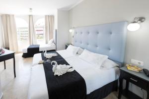 a bedroom with a large bed with swans on it at Hotel Toboso Chaparil in Nerja