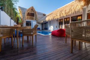 a deck with chairs and a table and a pool at Tricky Trees Lodges in Gili Islands