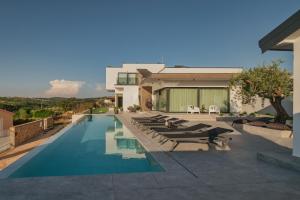a swimming pool with lounge chairs and a house at Villa KIM in Momjan