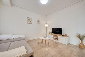 a white living room with a couch and a tv at Maturana by Clabao in Logroño