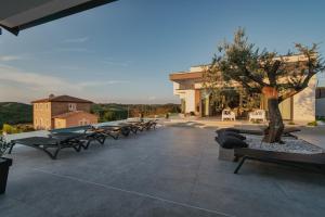 a patio with benches and a tree and a building at Villa KIM in Momjan