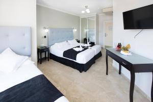 a bedroom with two beds and a desk and a television at Hotel Toboso Chaparil in Nerja