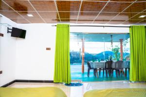 een eetkamer met groene gordijnen en een tafel bij Lina Eco Cottage - Ella in Ella