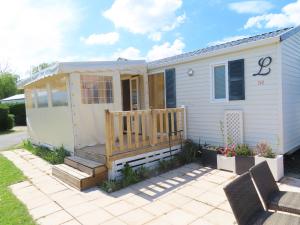 une petite maison avec un porche et une terrasse dans l'établissement Mobil home dans un camping 5 à Deauville, à Saint-Arnoult
