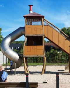 un toboggan dans une aire de jeux avec une personne dessus dans l'établissement Mobil home dans un camping 5 à Deauville, à Saint-Arnoult