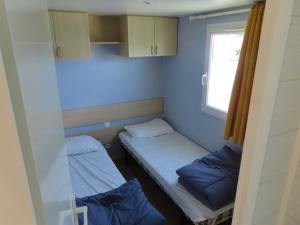 une petite chambre avec deux lits et une fenêtre dans l'établissement Mobil home dans un camping 5 à Deauville, à Saint-Arnoult 15 autres photos