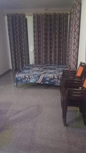 ein Bett in einem Zimmer mit Stühlen und Vorhängen in der Unterkunft Chandra Leelas Ashirwad Cottage in Mukteswar