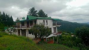 ein Haus mit einem grünen Dach auf einem Hügel in der Unterkunft Chandra Leelas Ashirwad Cottage in Mukteswar