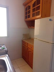 une cuisine avec un réfrigérateur blanc et des placards en bois dans l'établissement الصيف احلى فى الساحل, à El Alamein