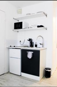 - une cuisine avec un comptoir noir et blanc et un évier dans l'établissement Appartement cosy Disneyland à 10 min Paris à 30 min, à Bussy-Saint-Georges